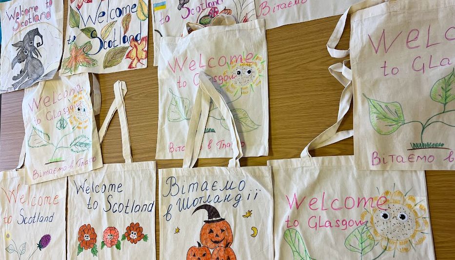 A display of canvas tote bags, decorated with welcome messages and picture doodles